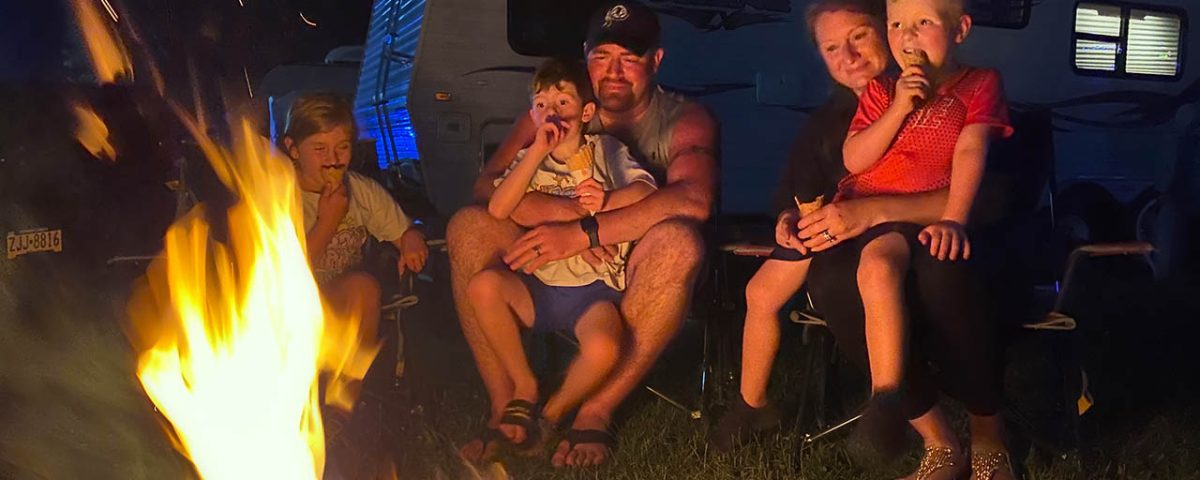 Family enjoying spring camping at Jellystone Park Mill Run with RV and campfire