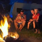 Family enjoying spring camping at Jellystone Park Mill Run with RV and campfire