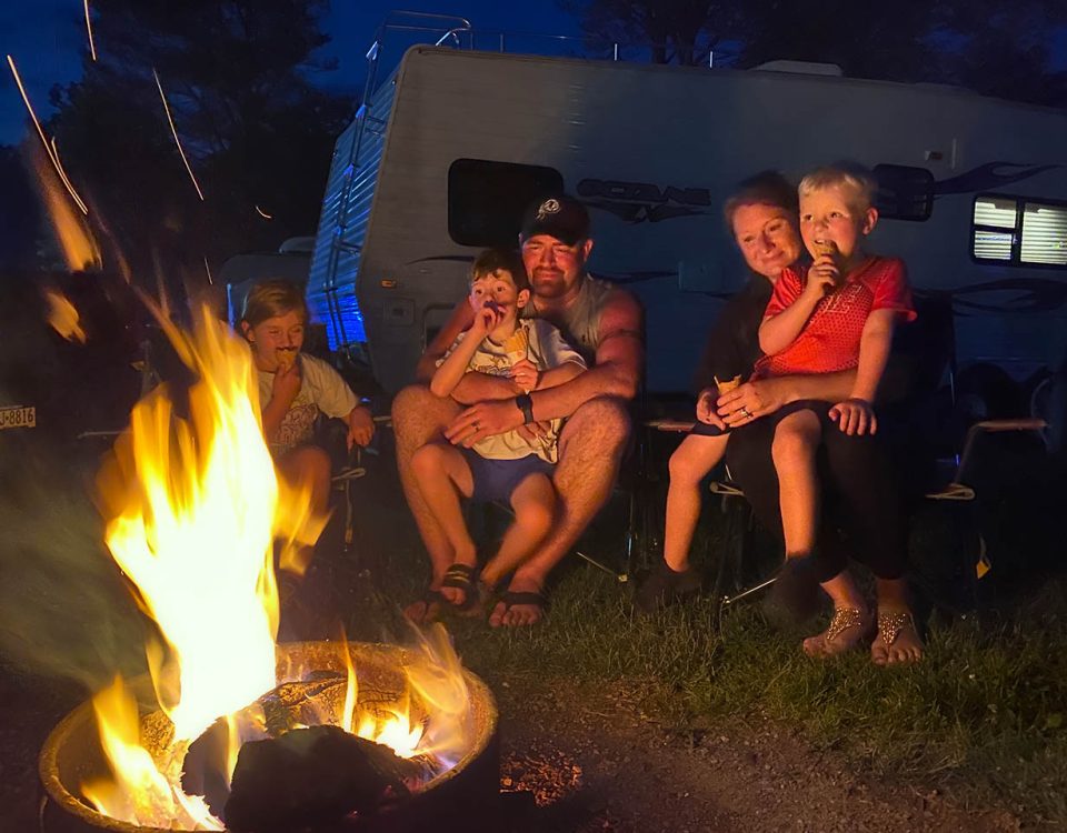 Family enjoying spring camping at Jellystone Park Mill Run with RV and campfire